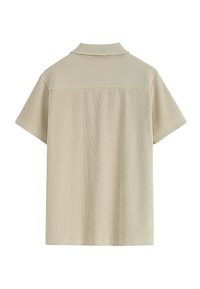 Polo beige à côtes avec manches courtes, doté d'un col structuré et d'un tissu texturé. La vue arrière présente un motif de rayures horizontales.