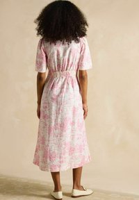 Rozā un baltā rakstainā kokvilnas kleita ar īsām piedurknēm, elastīgu jostasvietu un vidus teļiem garumu, ar ainavas un ainavu toile dizainu.