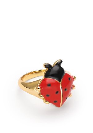 Anillo de oro con un diseño de mariquita roja y negra con pequeñas manchas negras en las alas, presentado sobre un fondo blanco.