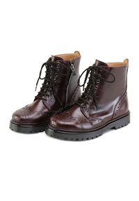 Botas de tobillo de cuero marrón con detalles de brogue perforados, cierre de cordones en la parte delantera, cremallera lateral y suela de goma negra con patrón de relieve.