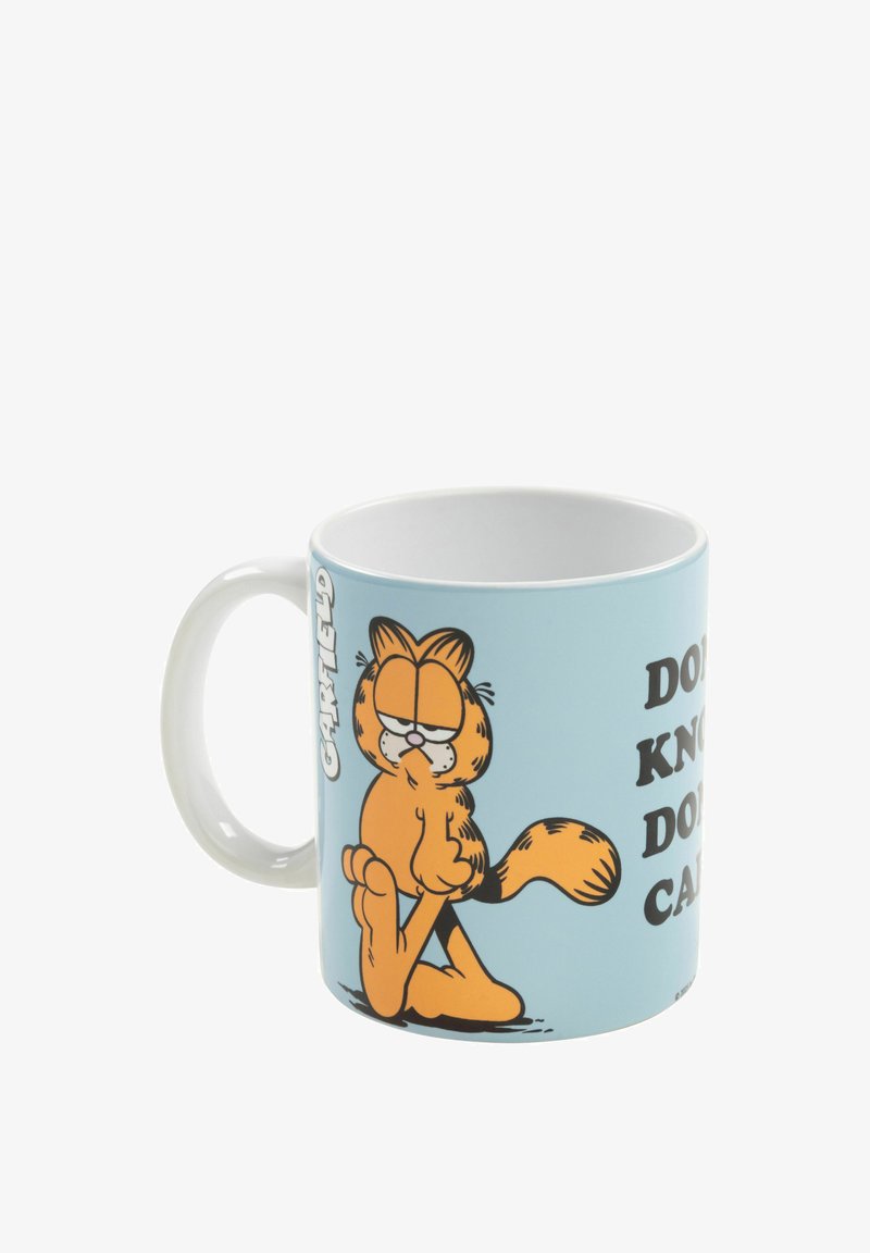 Mug in ceramica con un gatto in stile cartone animato su uno sfondo azzurro chiaro. Il testo dice: "NON SO, NON MI INTERESSA." Manico bianco, finitura lucida.