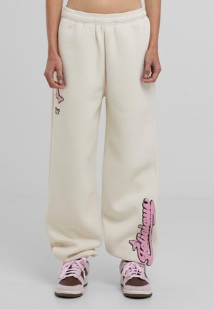 Crème-kleurige wide-leg sweatpants met roze geborduurde accenten van vlinders en tekst, voorzien van een elastische tailleband.