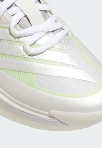 Close-up of white and pale green sneaker toe with mesh texture, white laces, and translucent synthetic overlays.