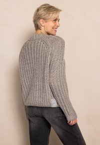 Chunky grey knitted sweater with a textured finish, relaxed fit, and ribbed design. Features a side logo tag and dropped shoulder seams.