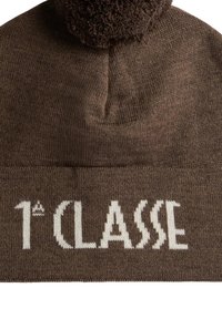 Berretto di lana marrone con finitura testurizzata, caratterizzato da un pon pon sulla cima e da testo bianco lavorato a maglia con la scritta "1^ CLASSE".