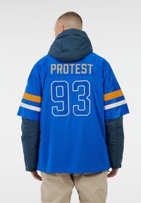 Blaue Mesh-Jersey mit teal Kapuze, versehen mit "PROTEST" und der Nummer "93" in goldenen, blauen und orangenen Akzenten. Lange Ärmel aus kontrastierendem Material.