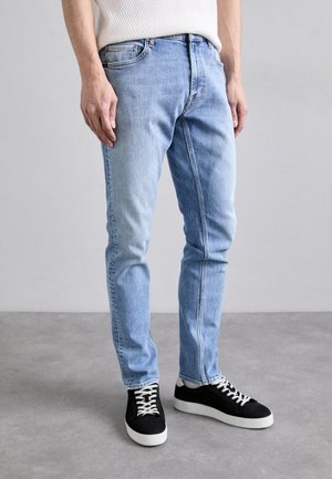 Lichtblauwe denim jeans met een slim fit, met subtiele vervaging, een vijf-pocket ontwerp en contraststiksel, gecombineerd met zwarte sneakers.