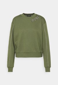 Sweat-shirt vert avec col rond, manches longues et logo "GUESS" brodé en strass sur l'épaule. Présente des accents de couture argentée.