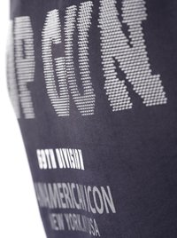 Mørkeblåt tekstil med fremtrædende hvid trykt tekst, der viser "TOP GUN" og "COTY DIVISION," med en glat, blød overflade.