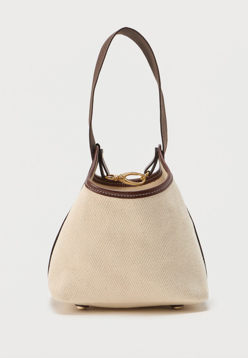 Μικρή μπεζ υφασμάτινη τσάντα με καφέ δερμάτινες λεπτομέρειες, έναν ώμο ιμάντα, χρυσό κούμπωμα και στρογγυλεμένη βάση με μεταλλικά ποδαράκια.