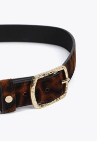 Bruine suède riem met patroon, voorzien van een gladde zwarte leren achterkant en een gestructureerde gouden gesp. Bevat metalen hardware en verstelbare gaatjes.
