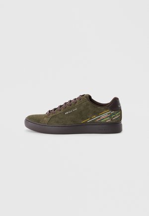 Basket en daim vert avec des détails brun foncé. Présente une semelle en caoutchouc et des accents rayés colorés sur le côté. Design à lacets sur le devant.