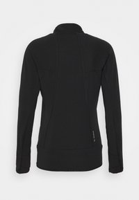 Svart trikåtröja i texturerat tyg med hög krage, med sömdetaljer och en liten logotyp på den nedre sidan.