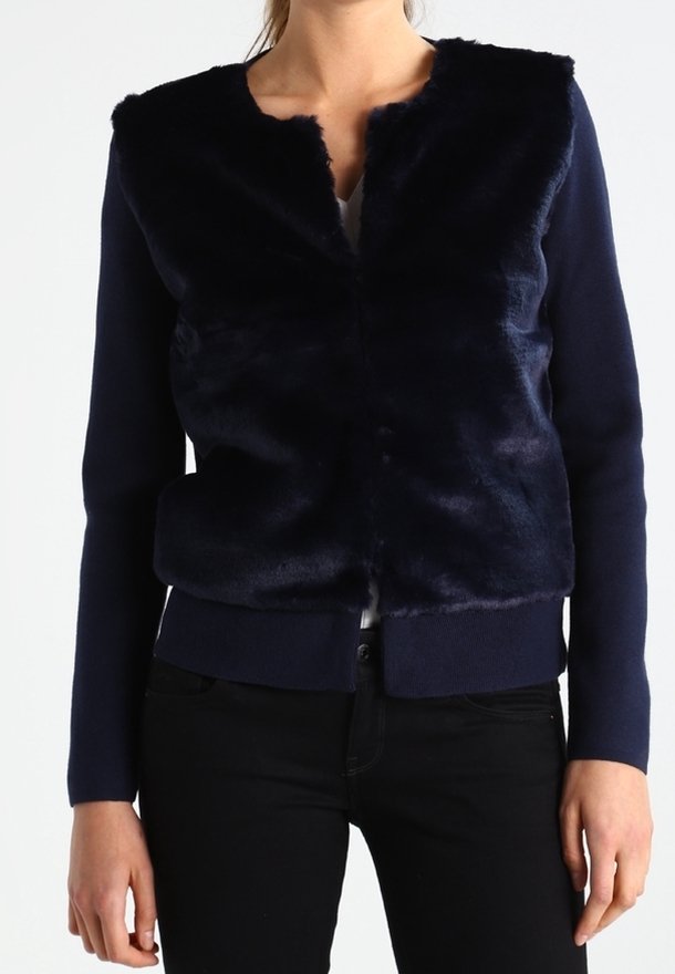 Kurtka z niebieskiego futerka sztucznego w kolorze granatowym, z zaokrąglonym kołnierzem, otwartym przodem i długimi rękawami. Charakteryzuje się gładką fakturą i ściągaczami przy mankietach oraz na dole kurtki.