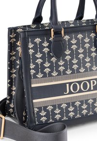 Dunkelblaue Handtasche mit cremefarbenem Blumenmuster, goldenen Hardware-Details und einem kontrastierenden cremefarbenen Streifen mit dem Markennamen "JOOP." Enthält einen Schultergurt.