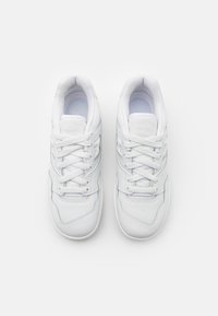 Bílé sportovní boty s hladkým koženým svrškem, kulatou špičkou, plochými tkaničkami a jemnými švy. Polstrovaná stélka a gumová podešev.