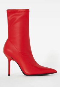 Červená kožená kotníková bota s špičatou špičkou, elegantní siluetou, vysokým stiletto podpatkem a bezšvovou konstrukcí svršku. Hladký povrch, žádné vzory.