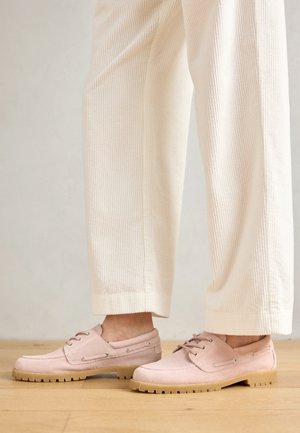 Le scarpe da barca in suede rosa chiaro presentano un design a profilo basso con lacci e una suola in gomma con scanalature testurizzate per la trazione.