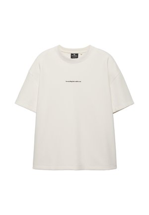 Bela majica s kratkimi rokavi, okroglim ovratnikom in majhnim črnim napisom "Ni vse, kar je vidno, resnično." na sredini prsnega koša.