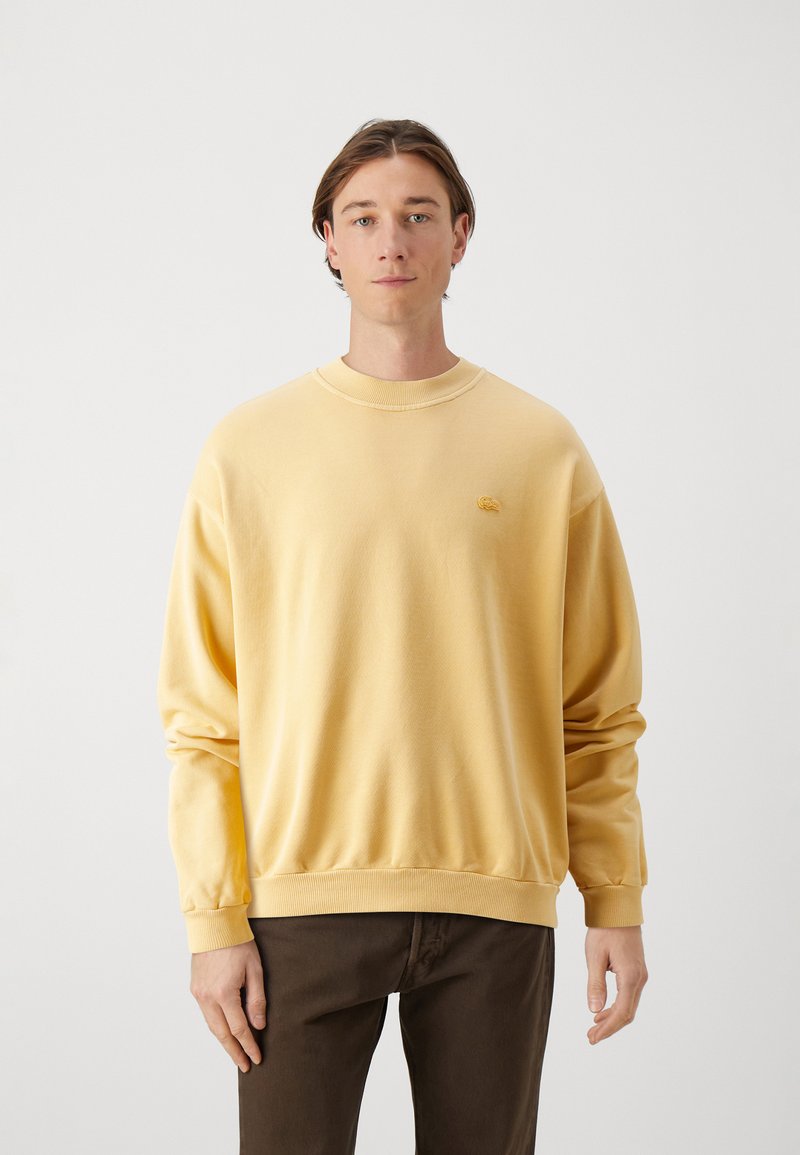 Geel katoen sweatshirt met een ribbelachtige ronde hals, lange mouwen en een klein borduurlogo op de borst. Gekozen met donkere broeken.