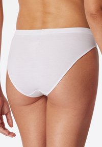 Slip di cotone bianco con texture a coste. Design a vita alta ai lati e morbida cintura elastica. Finitura liscia senza dettagli aggiuntivi.