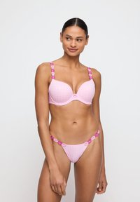 Lichtroze lingerieset met een gevoerde beha met een geruite textuur en bloemenbanddetails, vergezeld van bijpassende bikini-achtige onderbroeken.