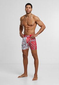 Piros és fehér mintás boxer alsónadrág márkás derékkal, részletes mintázattal és laza szabással, puha anyagból készült.