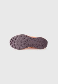 Semelle de chaussure de trail running présentant une surface en caoutchouc violet texturé avec des crampons triangulaires pour l'adhérence et un intermédiaire orange.