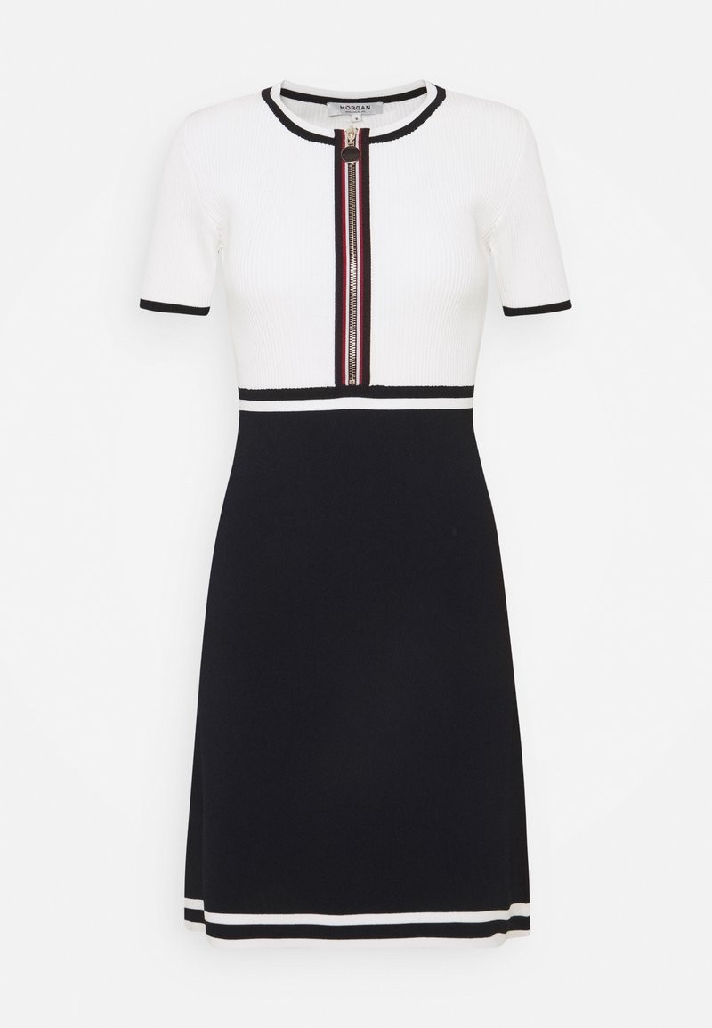 Robe tricotée blanche et marine avec des manches courtes, fermeture éclair à l'avant, bord noir et blanc rayé sur les manches et l'ourlet.