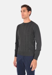 Maglione grigio scuro a maglia cable con scollatura rotonda, polsini e vita a coste, caratterizzato da un motivo testurizzato sul davanti.