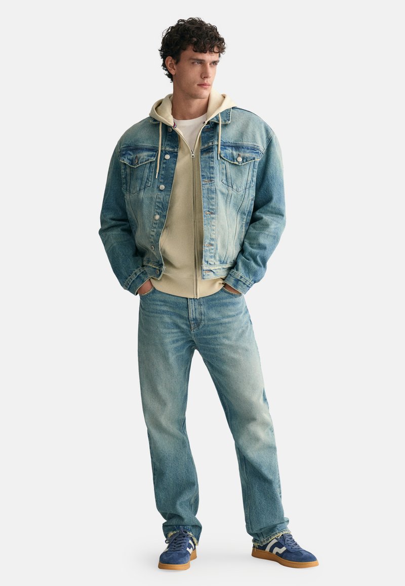 Himmelblaues Jeansjackett, cremefarbener Hoodie, himmelblaue Jeans und blaue Sneakers. Texturierte Materialien mit Vorderreißverschlusstaschen und lässiger Passform.