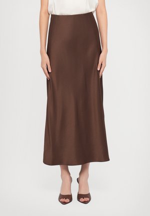 Brown satin maxi skirt with a smooth texture, high waist, and A-line silhouette, paired with brown heeled sandals.