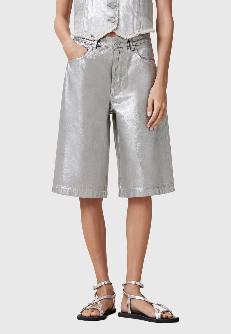 Metallic silver bermuda shorts with a loose fit, featuring side pockets and stitched hem. Paired with strappy silver sandals.