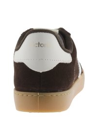 Zapatilla de ante marrón y cuero blanco con suela de goma color tostado, con forma redondeada y la marca "victoria" en el talón.