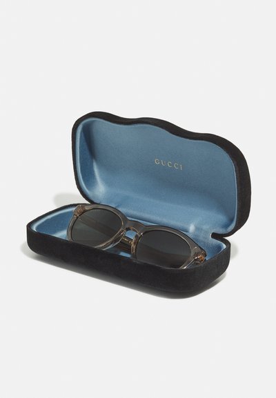 Gucci prillid mustas sametkarbis sinise siseküljega. Prillidel on läbipaistev raam ja tumedad läätsed.