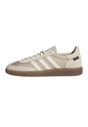 Baskets beige Adidas avec tige en daim et mesh, trois bandes blanches sur le côté, semelle en gomme et fermeture à lacets.