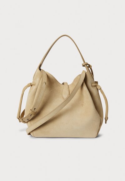 Bež žametna torbica vedro z zaobljenim zgornjim delom, kratkim ročajem in snemljivim naramnim trakom, z zapiranjem na vrvico in gladko teksturo.