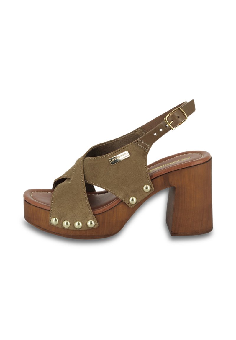 Zoccoli in suede marrone con plateau e un alto tacco in legno, design con cinturini incrociati e borchie decorative dorate lungo il bordo. Chiusura con fibbia sul cinturino.