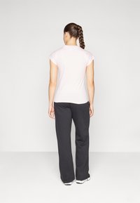 Light pink short-sleeve t-shirt with a round neckline, paired with black wide-leg pants and athletic shoes, viewed from the back.