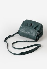 Groene leren tas met een zachte, gestructureerde oppervlakte, met een ronde vorm, een verstelbare schouderband en een centrale sluiting aan de bovenkant.