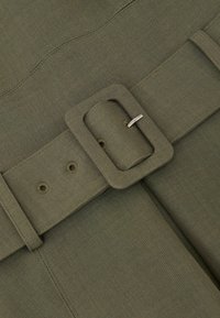 Oliiviroheline kangavöö ruudukujulise pandlaga, millel on viis auku reguleerimiseks. Tekstureeritud materjal nähtavate õmblustega.