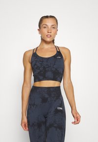 Μαύρο αθλητικό σουτιέν με σχέδιο tie-dye, με στρογγυλή λαιμόκοψη και πολλαπλές τιράντες. Συνδυάζεται με αντίστοιχες ψηλόμεσες κολάν. Και τα δύο είναι φτιαγμένα από ελαστικό ύφασμα.