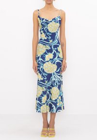 Robe maxi en bleu marine avec un motif floral jaune, bretelles fines, corsage ajusté et jupe fluide. Présente un décolleté drapé gracieux.