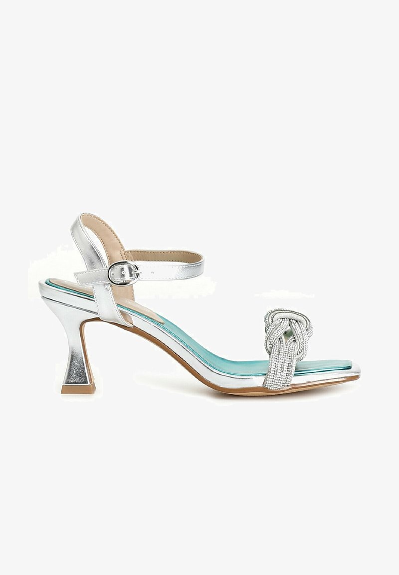 Silver heeled sandal with a braided strap, open toe, and ankle buckle. Features a contrasting turquoise insole and textured heel.