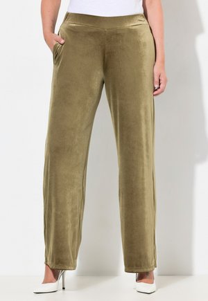 Pantalons larges vert olive en tissu doux et texturé, avec des poches latérales et une taille lisse, associés à des talons hauts blancs.