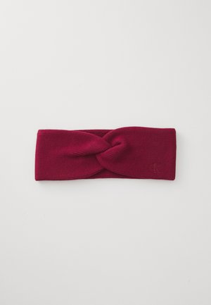 Burgundy knit headband featuring a twisted design at the front and a small embossed logo on the side. Soft texture and wide shape.