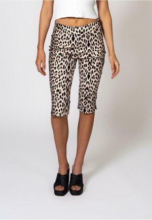 Pantalons capri à imprimé léopard avec une taille ajustée, en tissu extensible et d'une longueur mi-mollet, associés à des sandales à talons hauts noires tressées.