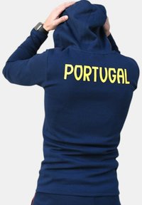 Sudadera azul marino con un diseño ajustado, con "PORTUGAL" impreso en amarillo brillante en la parte trasera. Tejido suave, estilo minimalista.