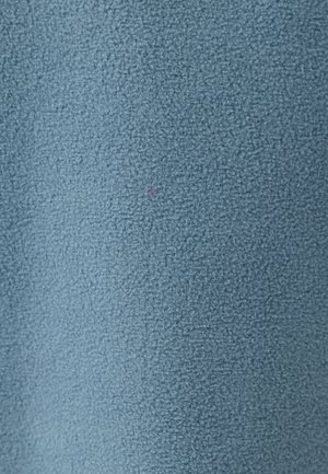 Tissu bleu texturé avec une surface douce et duveteuse. Le matériau semble uniforme, avec un léger éclat et une petite tache rose visible.