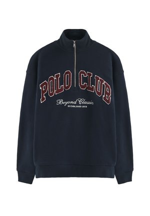 Sudadera azul marino con cuello alto, cierre de cremallera, bordado frontal "POLO CLUB" en color burdeos y texto "Beyond Classics". Tejido suave, ajuste holgado.
